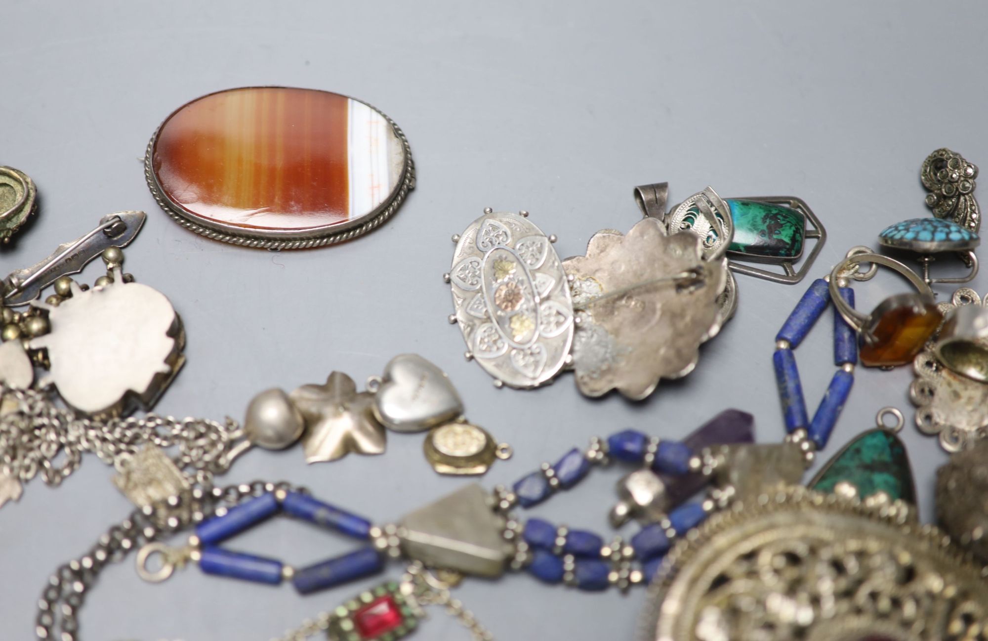 A mixed group of assorted white metal and costume jewellery including locket, brooches and filligree items.